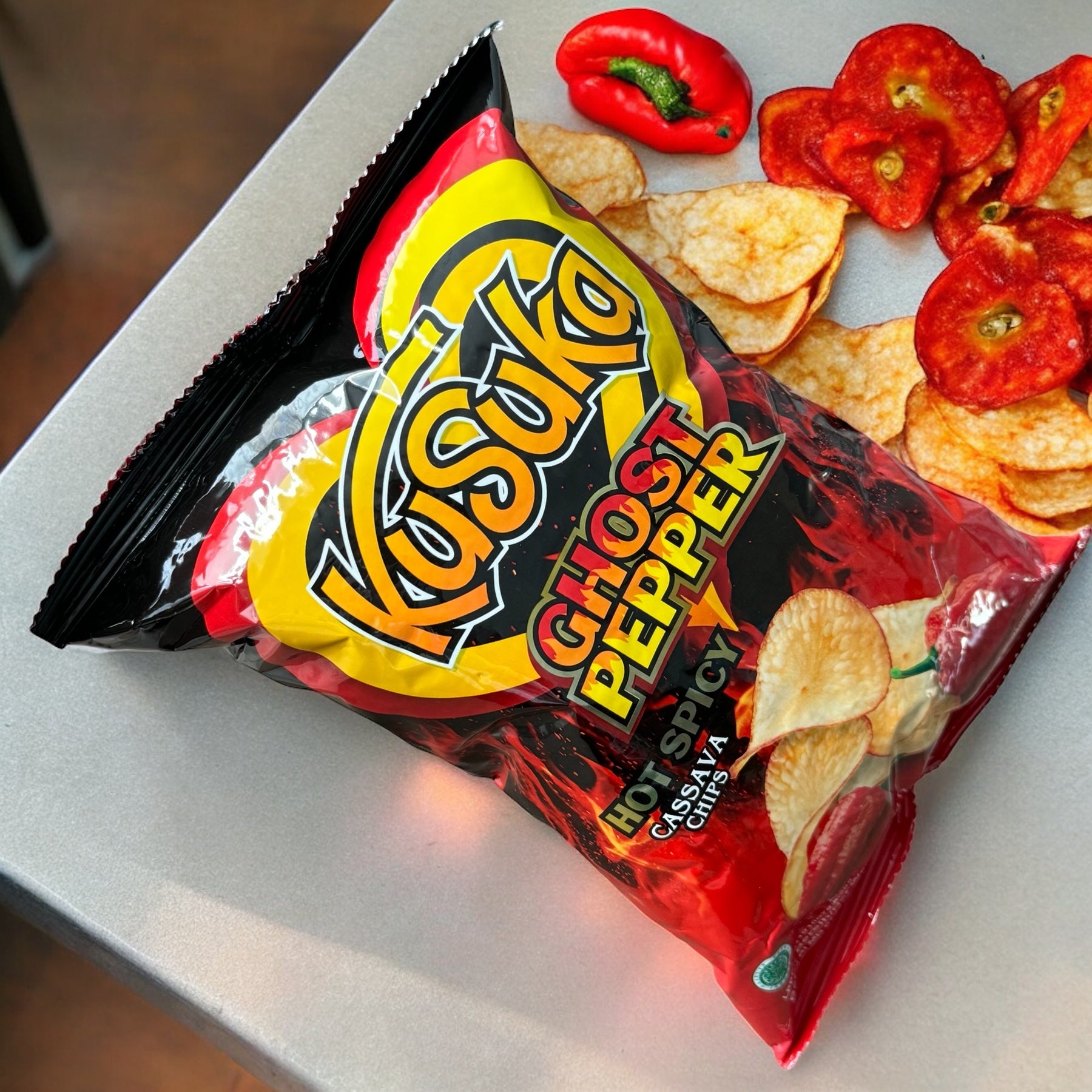 Knusprige Kusuka Keripik Singkong mit scharfem Setan-Chili-Geschmack, Nesia Food, in einer Verpackung auf einem Teller.