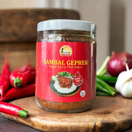 Sambal Geprek von Nesia, extra scharf, in einer weißen Schüssel mit roter Chili-Soße und frischen Kräutern auf einem Teller.