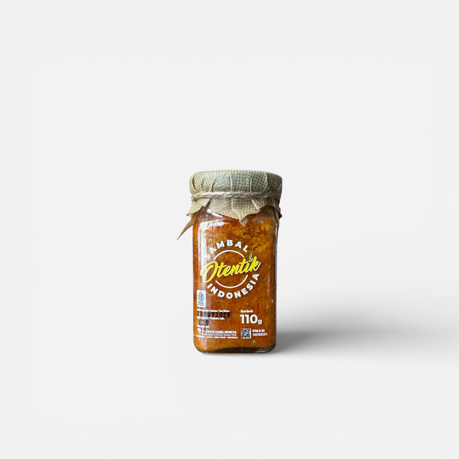 Chilisauce Otentik Sambal Bawang von Nesia in einer Glasflasche, mit roten Chilis und Knoblauch, auf einem weißen Hintergrund